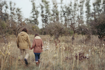 Young happy caucasian couple expecting a baby. Pregnant woman and her husband walking and having fun together outdoors in the autumn. Family, parenthood, love, happiness concept.