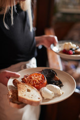 Close Up Of Waitress Working In Traditional English Pub Serving Breakfast To Guests