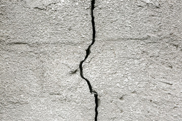 Concrete wall with a crack on it. Grey texture background.