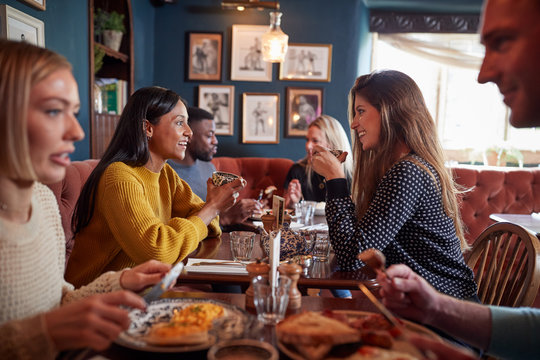 Group Of People Eating In Restaurant Of Busy Traditional English Pub