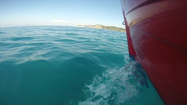 Front of red boat with waves splashing
