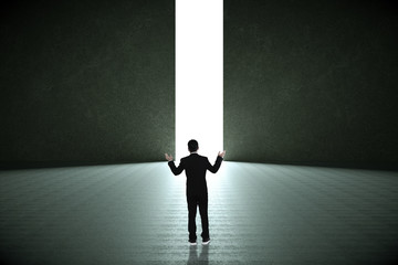 Obraz premium Businessman standing in a dark room and looking outside