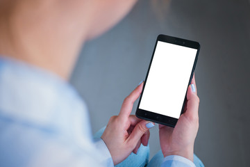 Mockup image: woman looking at black smartphone with white blank screen. Close up view of woman hands with smart phone mobile device. Mock up, copyspace, template and technology concept