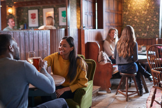 Couple Meeting For Lunchtime Drinks In Traditional English Pub Making A Toast