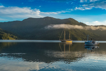 The calm waters of the Marlborough Sound, New Zealand, with calm waters and two boats sitting at anchor