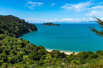 A view through the trees of a beach at the incredibly beautiful Able Tasman National Park, South Island, New Zealand