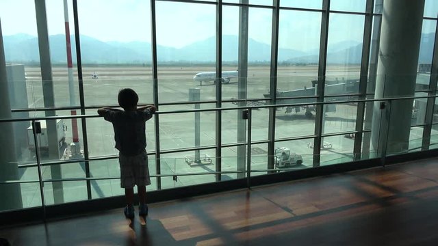 Dalaman Airport, Turkey - 18th of June 2019: 4K Silhouette of child watching a plane from airport window