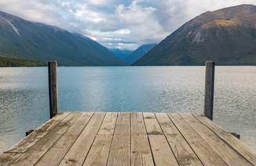 A view down a wooden jetty of the incredibly beautiful Rotoiti Lake surrounded by mountains which is part of the Nelson Lakes National Park
