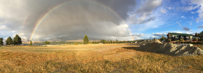 The beautiful full arch of a rainbow across a meadow in New Zealand