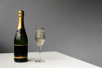 Champagne bottle and champagne glass on white table