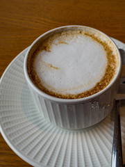 Close up hot cappuccino white coffee cup on brown old wood table at cafe