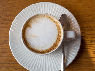 Close up hot cappuccino white coffee cup on brown old wood table at cafe
