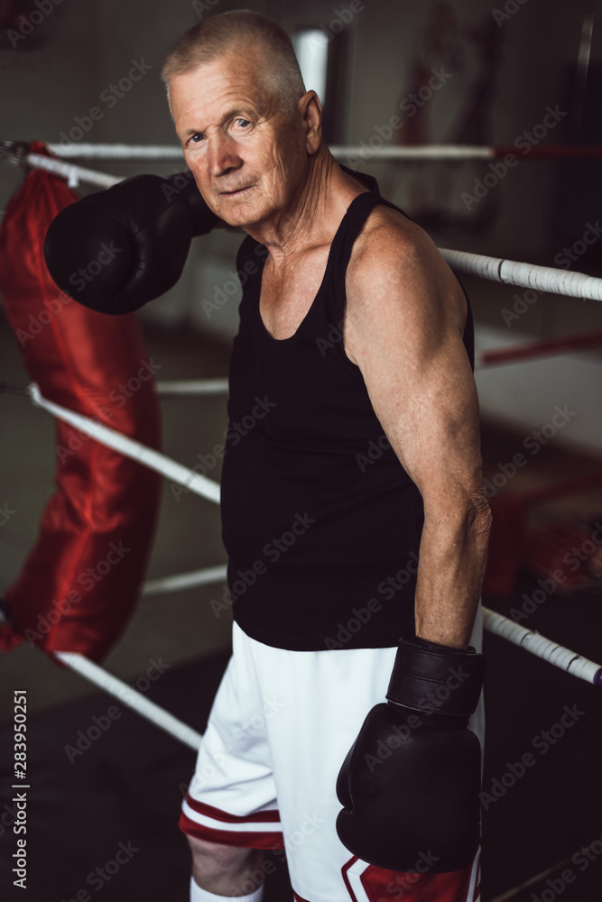 Wall mural senior boxer, man with black gloves in the ring