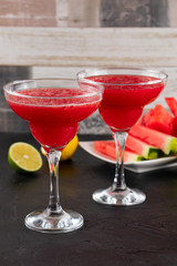 Two watermelon smoothies with slices of watermelon, lemon and lime