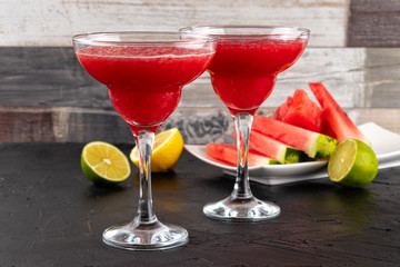 Two watermelon smoothies with slices of watermelon, lemon and lime