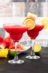 Two watermelon smoothies with slices of watermelon, lemon and lime