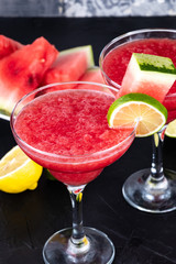 Two watermelon smoothies with slices of watermelon, lemon and lime