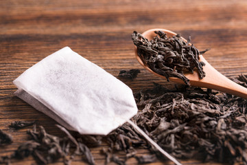 Tea bag on wooden background. Tea bag and tea leaves with a spoon on a wooden background.