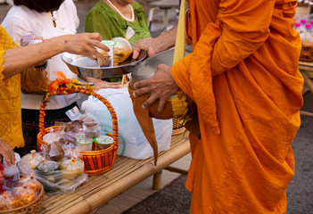 Thai people make merit by giving food to monks.