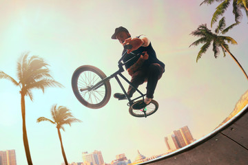 BMX rider is performing tricks in skatepark on sunset.