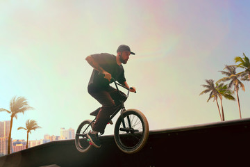 BMX rider is performing tricks in skatepark on sunset.