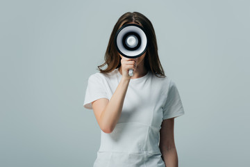 Fototapeta premium young pretty woman holding loudspeaker in front of face isolated on grey