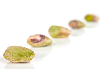 Group of five whole ripe green pistachio in closeup placed diagonally in line isolated on white background