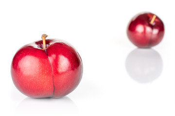 Group of two whole ripe red round plum placed diagonally in line isolated on white background