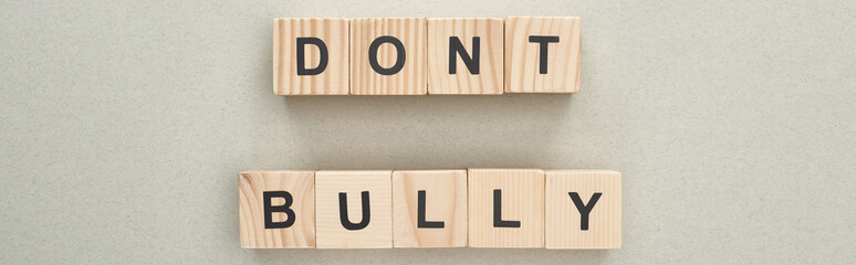 panoramic shot of wooden blocks with dont bully lettering on grey background