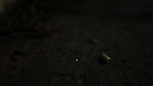 Forensic officer picking up 9mm bullet casing from alley