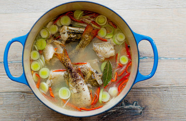 Ear cooked from river perch and vegetables. In a beautiful cast-iron pan. And she stands on a table made of wood.