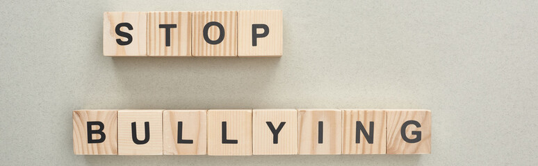 panoramic shot of wooden blocks with stop bullying lettering on grey background