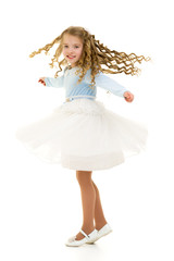 Fototapeta na wymiar A little girl in a dress is spinning.