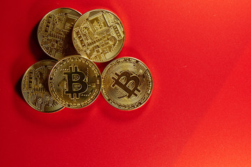 Physical golden coins bitcoins on a red background. Digital cryptocurrency concept