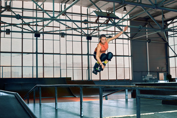 Rollerblader jump high from big air ramp performing trick. Indoors skate park equipment.