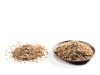 Cumin seeds (Cuminum), jeera in a clay plate and on a white background