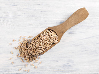 Cumin seeds (Cuminum), Jeera in a wooden scoop on a white wooden background