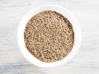 Cumin seeds (Cuminum), Jeera in a white cup on a white wooden background