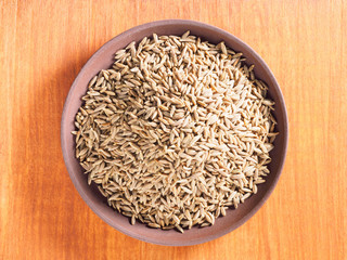 Cumin seeds (Cuminum), Jeera in a clay plate on a brown wood background