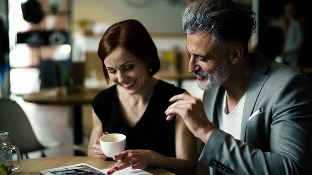 Man and woman having business meeting in a cafe, using tablet.