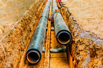 Underground pipe being fixed in trench. Man do a circular welding