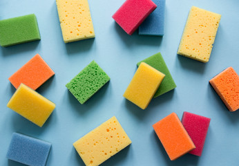 on a blue background lies a layout of different color sponges for cleaning the kitchen cleaning dishes flat lay