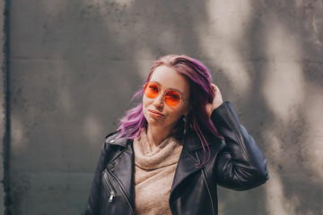 Woman in orange sunglasses and with colorful dyed hair.