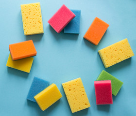 on a blue background lies a layout of different color sponges for cleaning the kitchen cleaning dishes