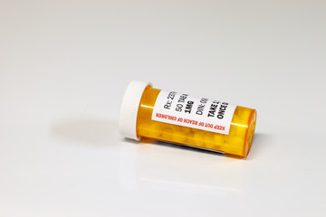Prescription drug bottle with generic tablets or pills isolated on a white background.