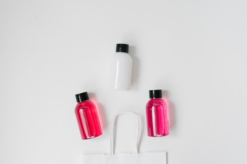 Set of cosmetic products for shower or bath, white and pink bottles in a paper white package on a white background.