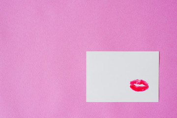 The kiss imprint is made with red lipstick on white paper with pink background. Copy space. Valentine's day card