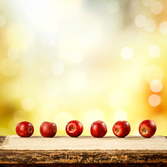 Red apples on the wooden table and blurred autumn background.