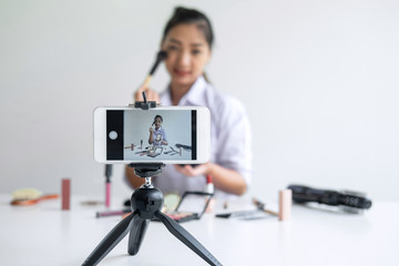 Naklejka premium Business online on social media, Beautiful Asian woman blogger is showing present tutorial beauty cosmetic product and broadcast live streaming video to social network while recording teaching online