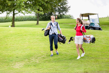 Golfing couple carrying their bags